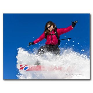 Girl snowboarding jumping through fresh powder post cards