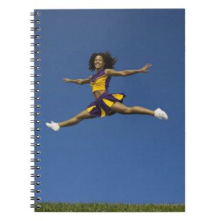 Female cheerleader doing jump splits in air note book