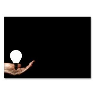 Floating lightbulb above hand on black background business cards