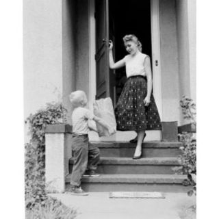 Boy giving shopping bag to mother outside house Poster Print (18 x 24)